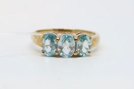 Three stone topaz ring, three oval cut blue topaz, claw set in 9ct yellow gold