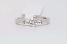 Three stone diamond ring, central round brilliant cut diamond, with a tapered baguette cut diamond