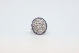 A sapphire and diamond panel ring in white metal. The geometric panel studded with diamonds, with