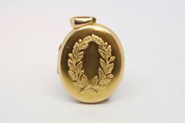 A yellow metal locket pendant with laurel wreath design. Tests as 15ct gold. 25.2g 5.5cm in length.