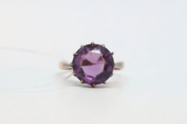 Purple paste ring, claw set in yellow metal tested as 9ct