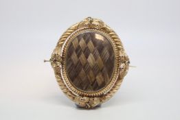 An elaborate hair work mourning swivel brooch in yellow metal. Both sides feature finely woven hair.