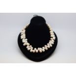 Pearl necklace, set with oval shaped pink, cream and grey pearls in an unusual design, on a yellow