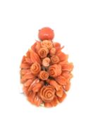 A carved coral pendant, carved open roses and closed buds surrounded by carved leaves, each on