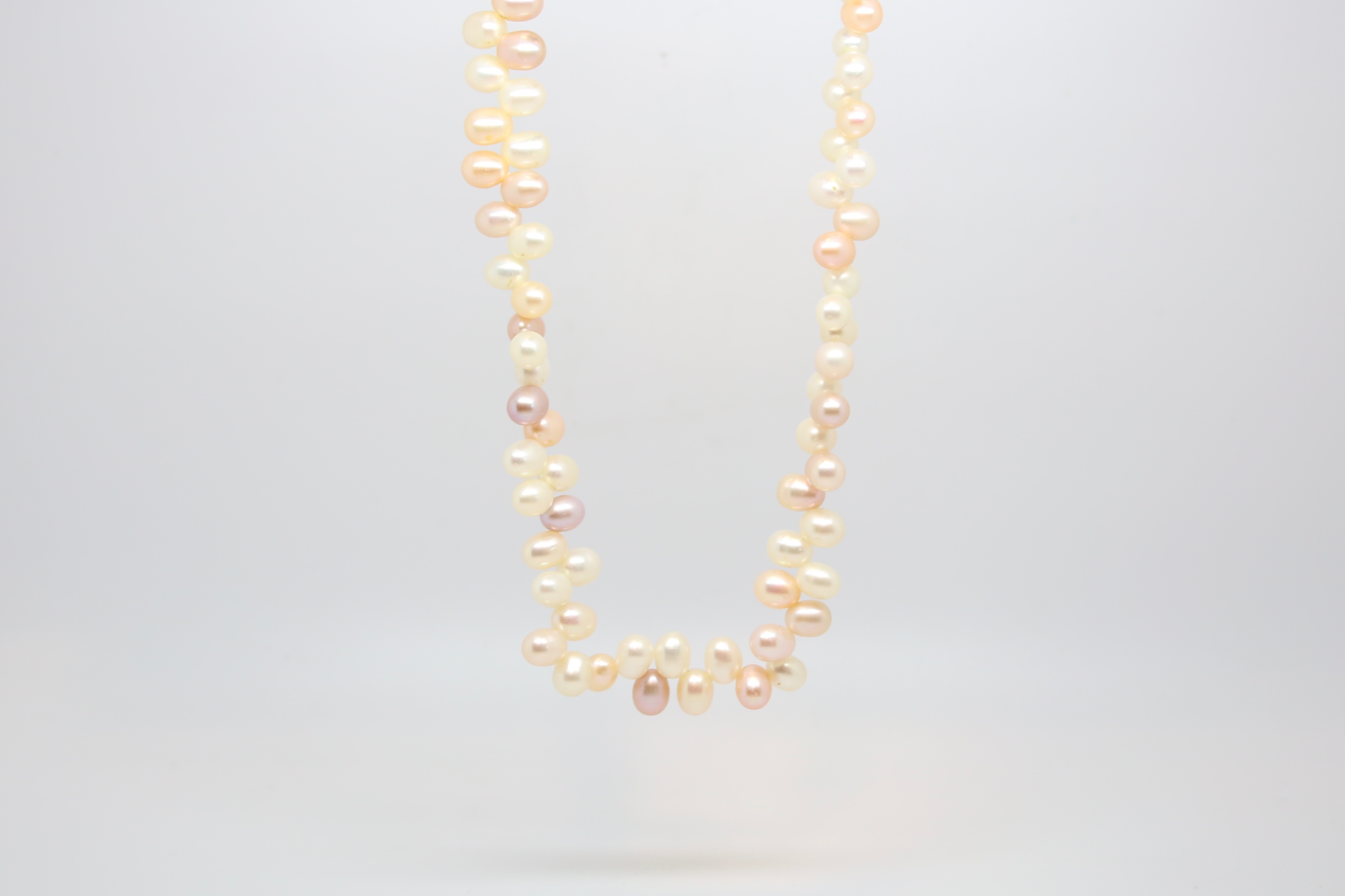 Pearl necklace, set with oval shaped pink, cream and grey pearls in an unusual design, on a yellow - Image 2 of 2