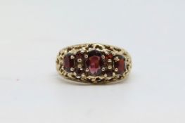Vintage three stone garnet ring, oval cut garnets in a textured open work surround, mounted in 9ct
