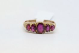 An almandine garnet five stone band, in yellow metal. Ring size S 1/2.