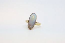 An opal dress ring, the vertically set opal in a closed back yellow metal setting, ring size V1/2