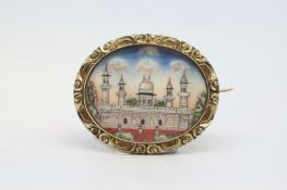 An antique yellow metal brooch with a hand painted panel depicting an Eastern building.