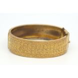 Base metal gold coloured clasp bangle, engraved detail to half the hoop, with safety chain, inside