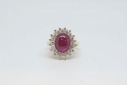 Cabochon ruby and diamond cluster ring, central 13x9mm cabochon cut ruby, within a double row border