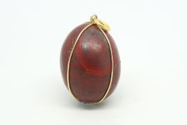 Red jasper egg pendant, with a yellow metal wire surround stamped 18ct