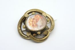 Brooch, central image of a cameo behind a plastic pane, gilt metal knot border, with a locket back