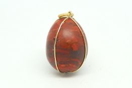 Red jasper egg pendant, with a yellow metal wire surround stamped 18ct