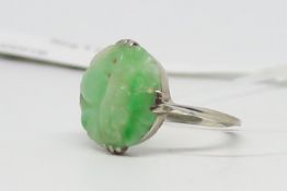 Single stone jade ring, circular carved jade panel, claw set in white metal, ring size K