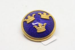 Enamel and yellow metal circular pin, blue enamel with three yellow metal crowns, set in yellow