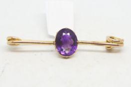 Amethyst bar brooch, oval cut amethyst set on a yellow metal safety pin style bar brooch