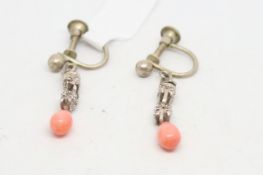 Pair of silver and coral drop earrings, tear drop coral suspended from a carved silver drop, screw