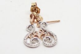 Diamond drop earrings, diamond set swirl design in rose metal stamped and tested as 9ct