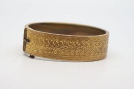 Base metal gold coloured clasp bangle, engraved detail to half the hoop, with safety chain, inside