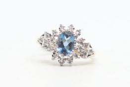 Topaz and diamond cluster ring, central oval cut blue topaz, surrounded by illusion set diamonds,