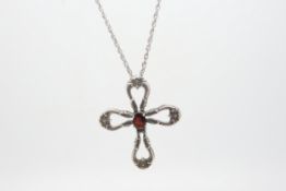 Silver and garnet cross pendant, oval cut garnet set in the centre of an openwork scrollwork