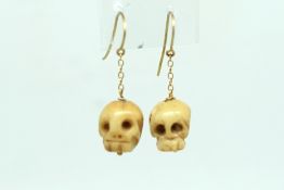 Pair of bone drop earrings, carved as skulls, on gold wires