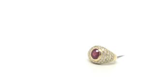 French ruby and diamond ring, central oval cut ruby rubover set in a bombé style cluster of round