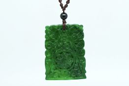 A carved jade pendant, a finely carved jade plaque pendant, on a rope necklace