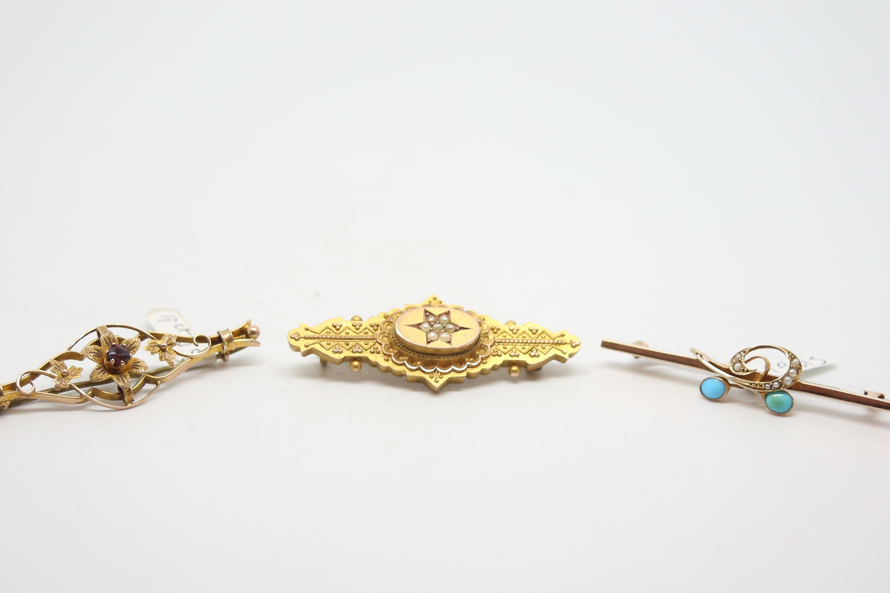 Three bar brooches, including a garnet set brooch, a turquoise and seed pearl brooch and a seed