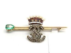 Gem set brooch, diamond set monogram, beneath an enamel and pearl crown, on a yellow metal bar,