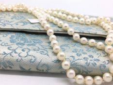 A single row of good Akoya quality pearls, strung knotted, with vintage Mikimoto silk cases,