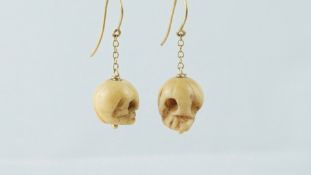 A pair of bone earrings in the form of skulls