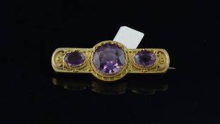 Amethyst brooch, three round cut amethysts with beading detail, set in yellow metal tested as