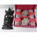 Carved oriental god figure and a boxed set of cups and saucers