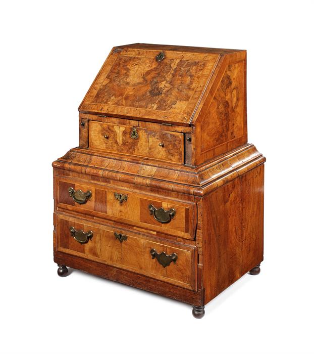 A rare George I walnut, crossbanded and featherbanded child's bureau on a later base