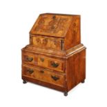 A rare George I walnut, crossbanded and featherbanded child's bureau on a later base