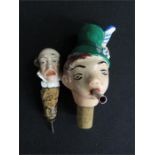 Two German porcelain top bottle stoppers, with caricature heads, largest 12cm hihgh.