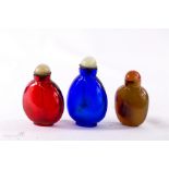 Three Chinese scent bottles, two glass in red and green, and one in agate, all with stoppers,