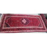 A hand woven rug, with central motif, stylised red ground borders, 11ft2 by 5ft2.