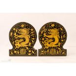 A pair of Chinese book ends, ebonised and gilded and depicting dragons.