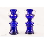 A pair of blue glass urn form vases.