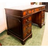 A pedestal desk with red leatherette skivver.