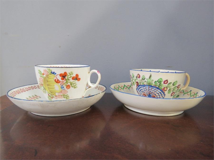 Two early pottery hand painted cups and saucers.