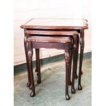 A nest of mahogany glass top occasional tables.