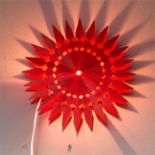 Two Swedish wooden wall lights in red, of geometric sunburst pattern, 28cm diameter.