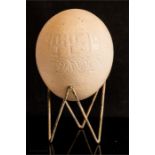 A carved ostrich egg raised on a stand.