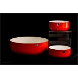 A trio of red enamel bowls with label 'Arabia Finland', one large, diameter 26cm two smaller bowls