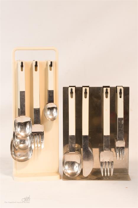 Two sets of cutlery: Abert and Nicrosl 18/12 on free standing racks with cream plastic handles.
