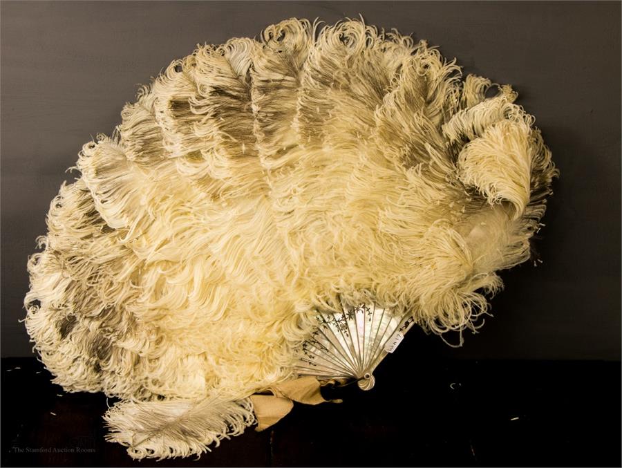 A late 19th century mother of pearl and ostrich feather fan, with silvered floral detail.